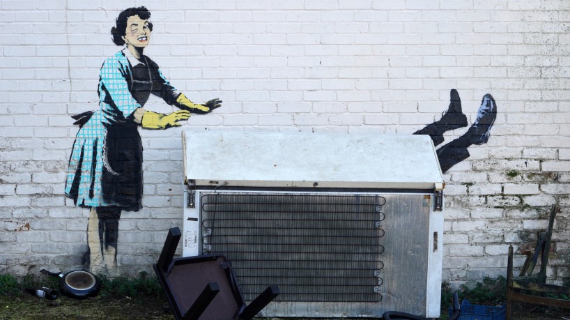 O mural de Banksy retrata uma dona de casa, com um olho roxo e um dente quebrado, empurrando um homem para dentro de um freezer