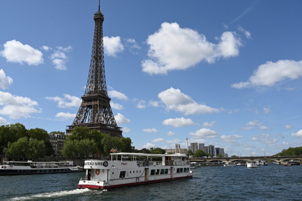 Um barco de Peniche passa pela Torre Eiffel no rio Sena a 17 de julho de 2023, durante um desfile para testar "manobras", "distâncias", "duração" e "captura de vídeo" da futura cerimónia de abertura dos Jogos Olímpicos de Paris em 2024 Para este mini-ensaio, a frota total é composta por 57 barcos, 39 representando as delegações - pouco menos da metade do Dia D em 2024 - e outros 18 dando apoio (assistência, primeiros socorros) e Olympic Broadcasting Services (OBS), a emissora de TV olímpica.(Foto: Bertrand GUAY / AFP)