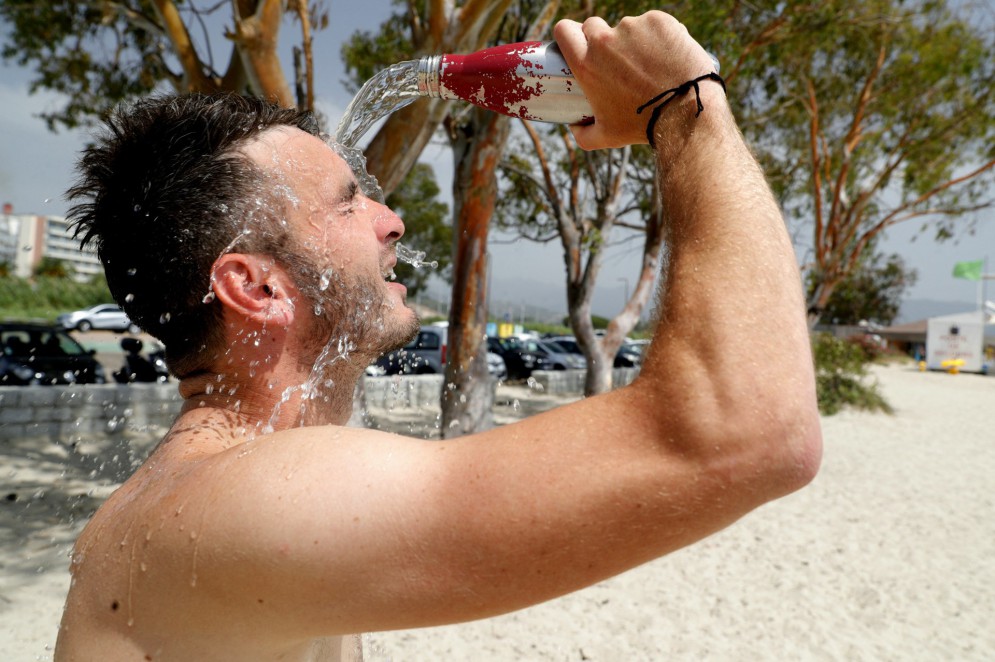Homem se refresca na praia de Ricanto, Ajácio, na Ilha de Córsega, na França, durante onda de calor(Foto: Pascal POCHARD-CASABIANCA / AFP)