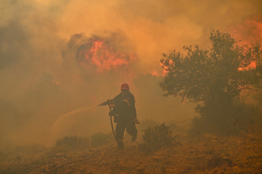Bombeiro combate incêndio florestal próximo a Atenas, na Grécia, durante onda de calor(Foto: Louisa GOULIAMAKI / AFP)