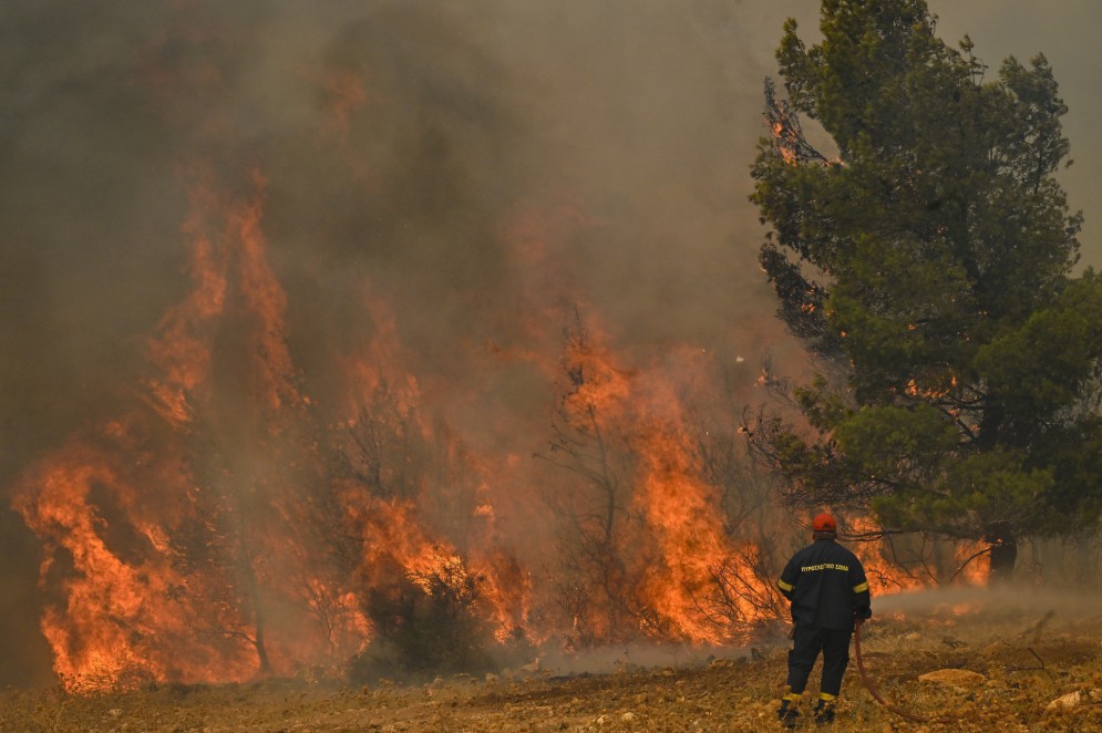 Bombeiro diante de incêndio florestal próximo a Atenas, na Grécia, durante onda de calor(Foto: Louisa GOULIAMAKI / AFP)