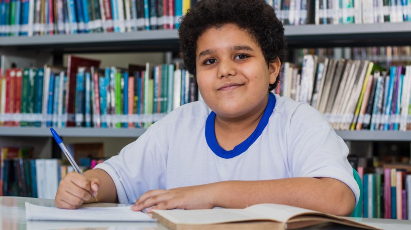 Na foto, João Gabriel, aluno do Ensino Fundamental, em um de seus lugares favoritos: a biblioteca