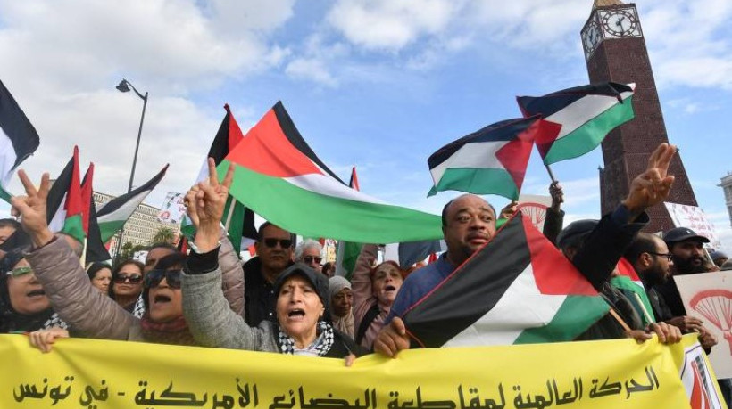  Na Tunísia, manifestantes exibem bandeiras da Palestina e faixa em árabe que pede um boicote aos Estados Unidos pelo apoio a Israel na guerra contra o Hamas em Túnis