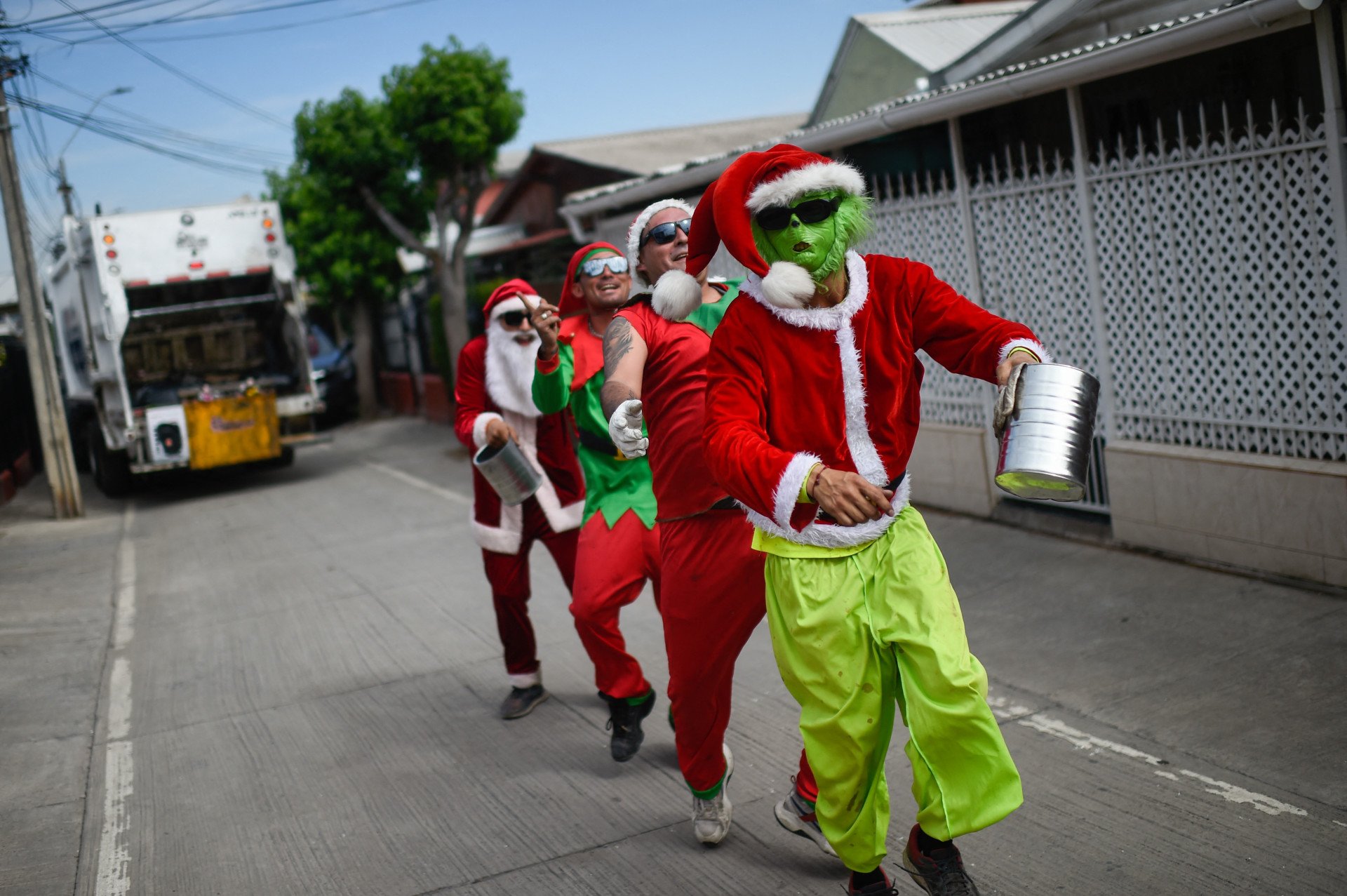 Chile – Catadores de lixo do município de Puente Alto vestidos como personagens natalinos coletam gorjetas enquanto recolhem o lixo na véspera de Natal, em Santiago, no dia 23 de dezembro de 2023.
 (Foto: Pablo VERA/AFP)