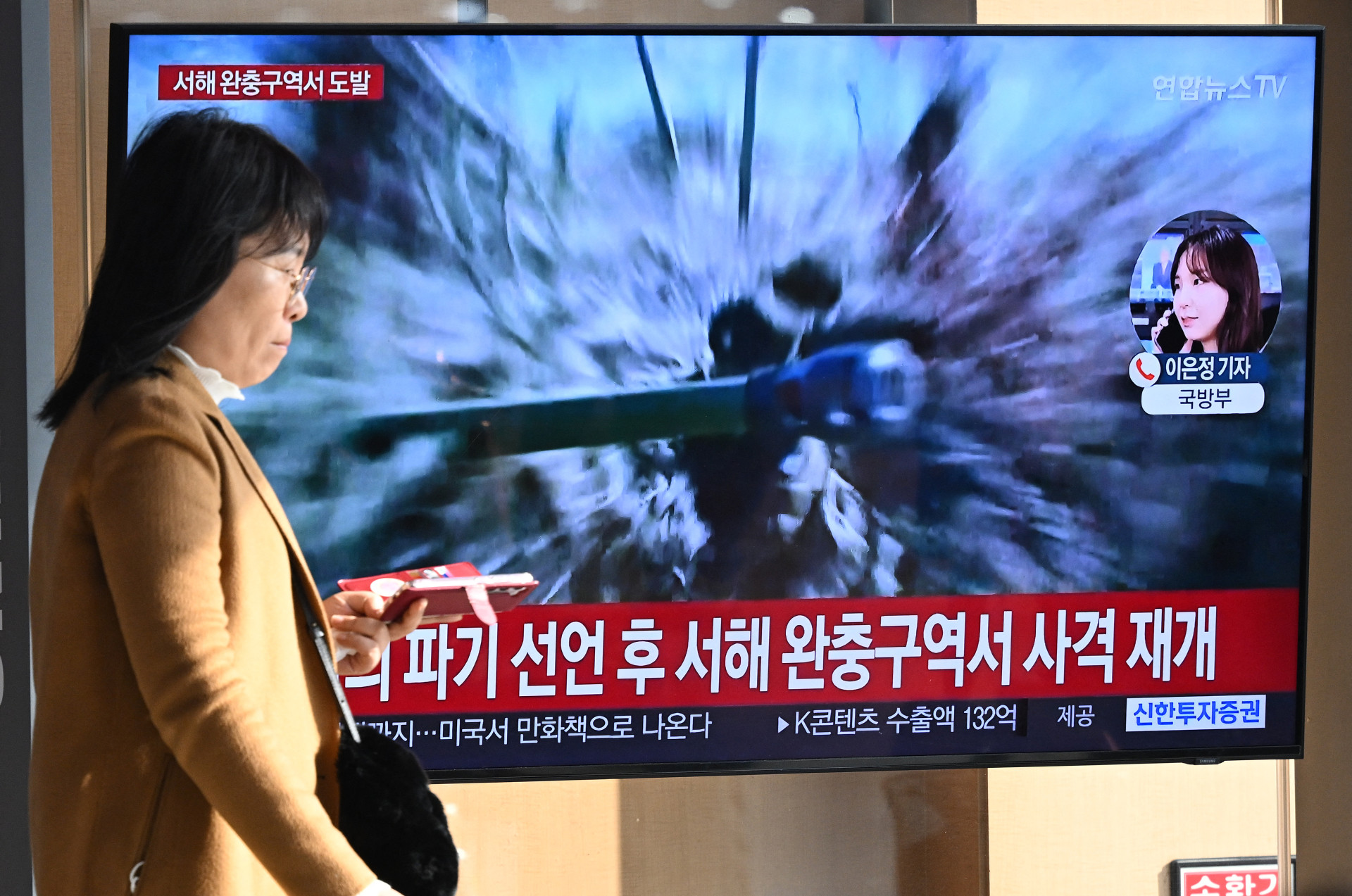 Uma mulher passa por uma tela de televisão que mostra um noticiário com imagens de arquivo dos disparos de artilharia da Coreia do Norte, em uma estação ferroviária em Seul, em 5 de janeiro de 2024.
A Coreia do Norte disparou mais de 200 projéteis de artilharia perto de duas ilhas sul-coreanas em 5 de janeiro, disse o Ministério da Defesa de Seul, com uma ordem de evacuação emitida para os residentes de uma delas.
 (Foto: Jung Yeon-je/AFP)