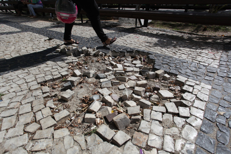 Piso da Praça do Ferreira, em Fortaleza, tem buracos e pedras de calçamento soltas

