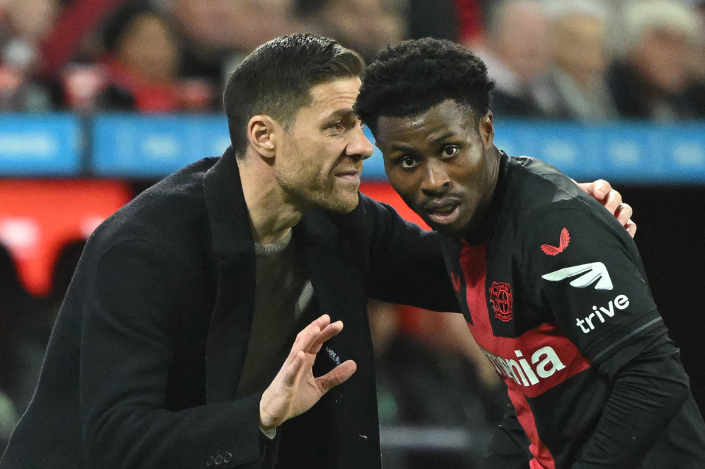 Xabi Alonso passa orientações a Jeremie Frimpong em jogo do Leverkusen(Foto: INA FASSBENDER / AFP)