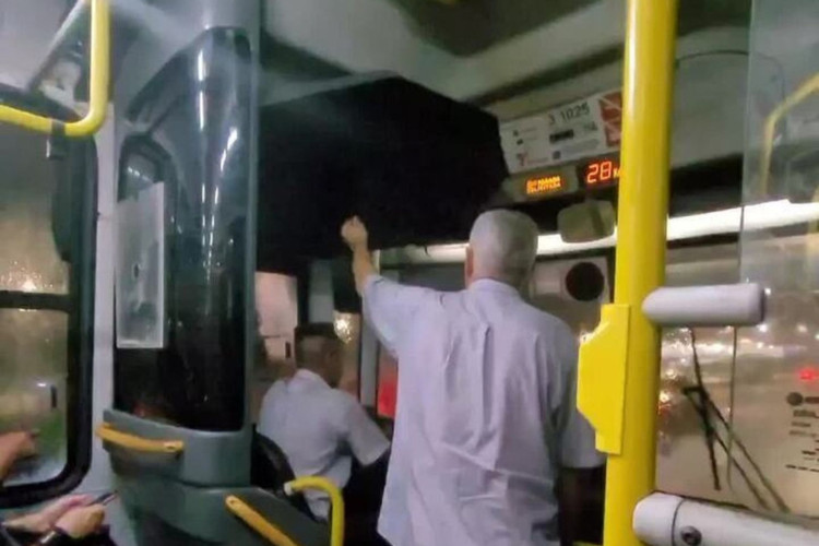 Cobrador é flagrado segurando guarda-chuva para motorista em ônibus com goteira