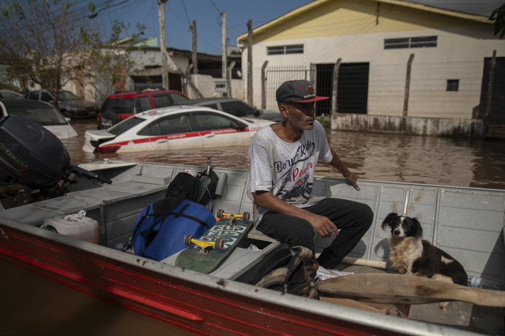 Um homem navega em um barco em uma rua inundada de Eldorado do Sul, Rio Grande do Sul, Brasil, em 9 de maio de 2024. (Foto: Carlos FABAL/AFP)