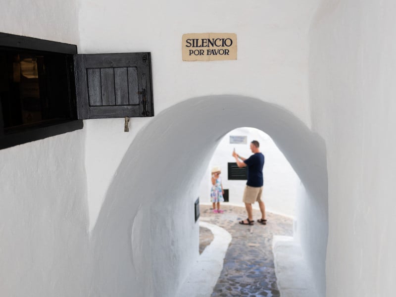 Turista tira uma foto enquanto uma placa diz "Silêncio, por favor" em Binibeca, uma pequena vila de pescadores no município de Sant Lluis, na ilha balear de Menorca