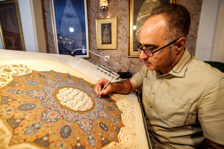 Mohammad Hossein Aghamiri, artista especializado em miniaturas persas, trabalha em uma de suas peças que retrata al-Fatiha, o primeiro capítulo do Alcorão 