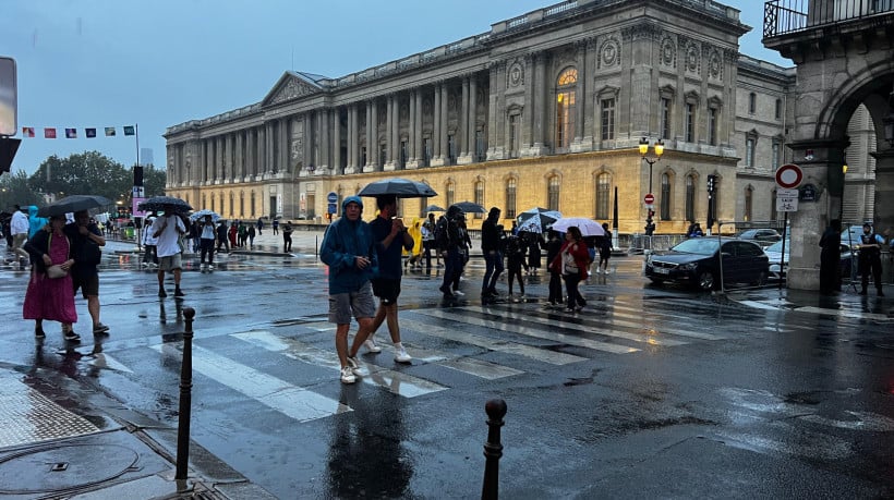 Público caminha sob a chuva em Paris durante a cerimônia de abertura das Olimpíadas 