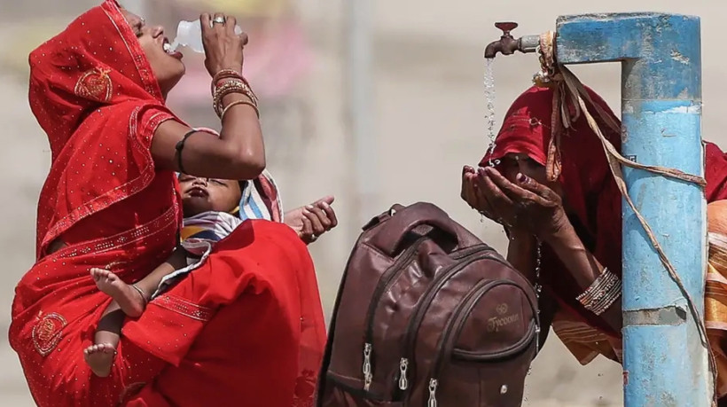 Mulheres se hidratam durante onda de calor em Prayagraj, na Índia: idosos, crianças, doentes e pobres são os mais vulneráveis ao calor extremo 