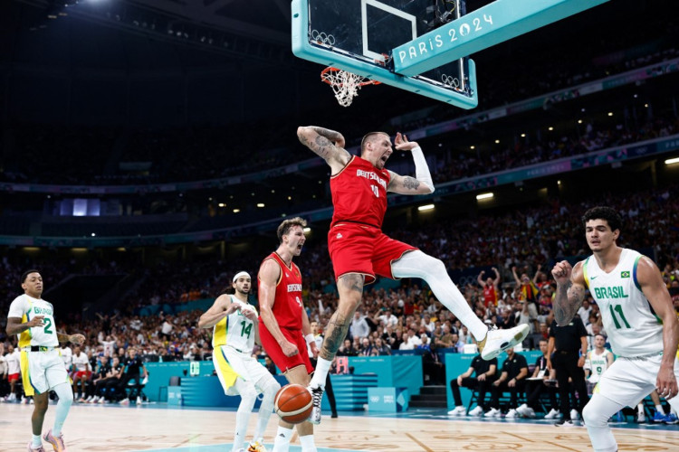 O número 10 da Alemanha, Daniel Theis, enterra a bola na partida preliminar masculina de basquete do grupo B entre Brasil e Alemanha durante os Jogos Olímpicos de Paris 2024, no estádio Pierre-Mauroy em Villeneuve-d'Ascq, norte da França, em 30 de julho de 2024.