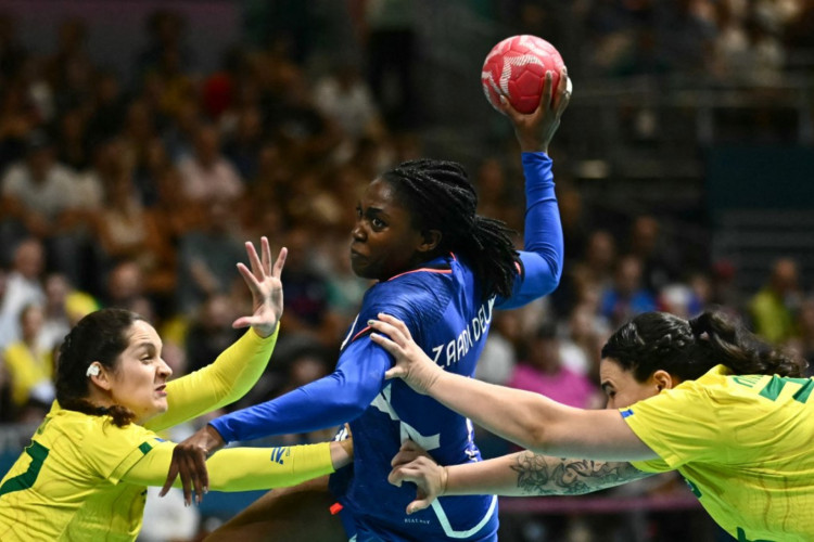 A ala esquerda francesa Grace Zaadi Deuna (C) tenta marcar para a lateral esquerda brasileira #77 Kelly Rosa durante a partida de handebol feminina do Grupo B da rodada preliminar feminina entre França e Brasil dos Jogos Olímpicos de Paris 2024, na Arena Paris Sul, em Paris, em 30 de julho. , 2024