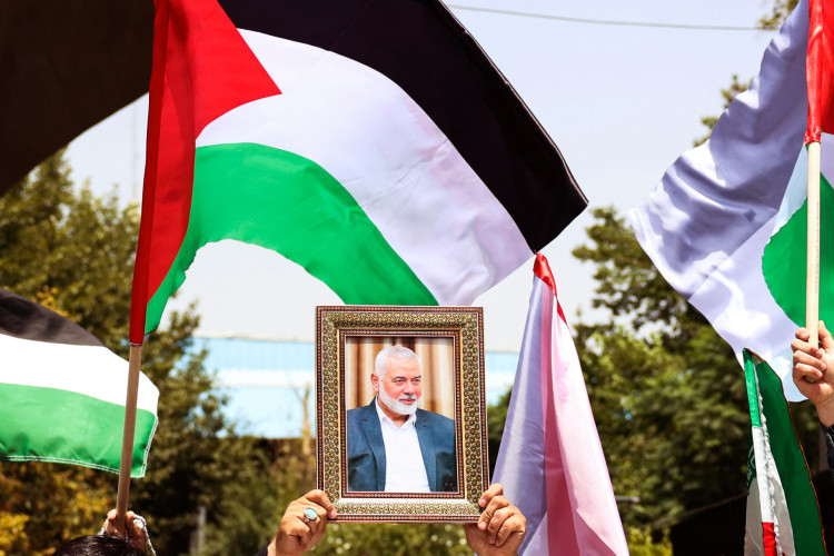 Pessoas seguram a bandeira palestina e um retrato do chefe do Hamas assassinado, Ismail Haniyeh, durante um ato na Universidade de Teerã, na capital iraniana