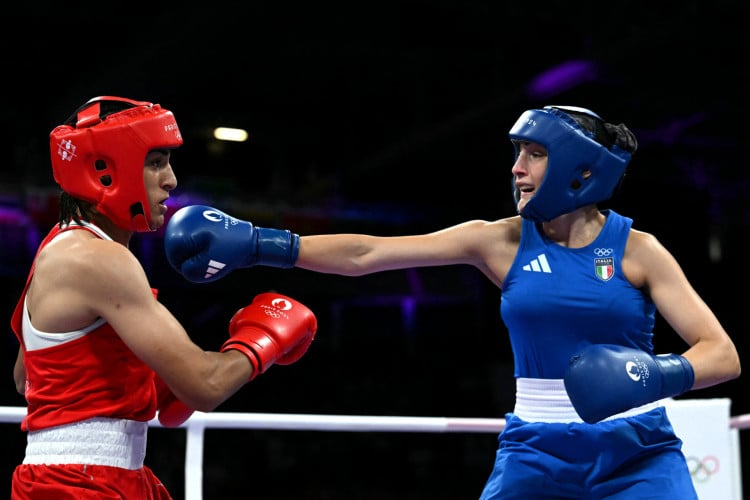 Imane Khelif, da Argélia (de vermelho), leva um soco da italiana Angela Carini na luta preliminar feminina de boxe das oitavas de final até 66 kg durante os Jogos Olímpicos de Paris 2024, na North Paris Arena, em Villepinte, em 1º de agosto de 2024 