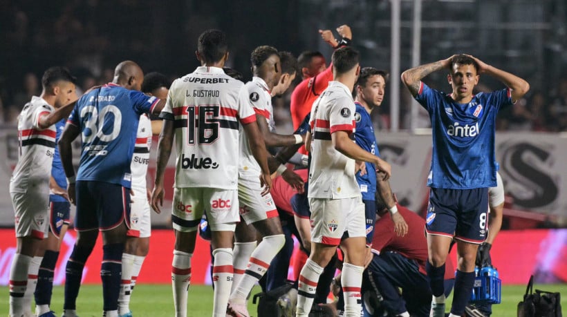 O zagueiro do Nacional, Juan Manuel Izquierdo (coberto), recebe atendimento médico após desmaiar durante a partida de volta das oitavas de final da Copa Libertadores entre o São Paulo do Brasil e o Nacional do Uruguai no estádio MorumBIS em São Paulo, Brasil, em 22 de agosto de 2024.
