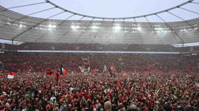 Leverkusen fans celebrate on the pitch after the German first division Bundesliga football match Bayer 04 Leverkusen v Werder Bremen in Leverkusen, western Germany, on April 14, 2024. Bayer Leverkusen were crowned 2023-24 Bundesliga champions for the first time on April 14, 2024.  (Photo by INA FASSBENDER / AFP) / DFL REGULATIONS PROHIBIT ANY USE OF PHOTOGRAPHS AS IMAGE SEQUENCES AND/OR QUASI-VIDEO (Photo by INA FASSBENDER/AFP via Getty Images)