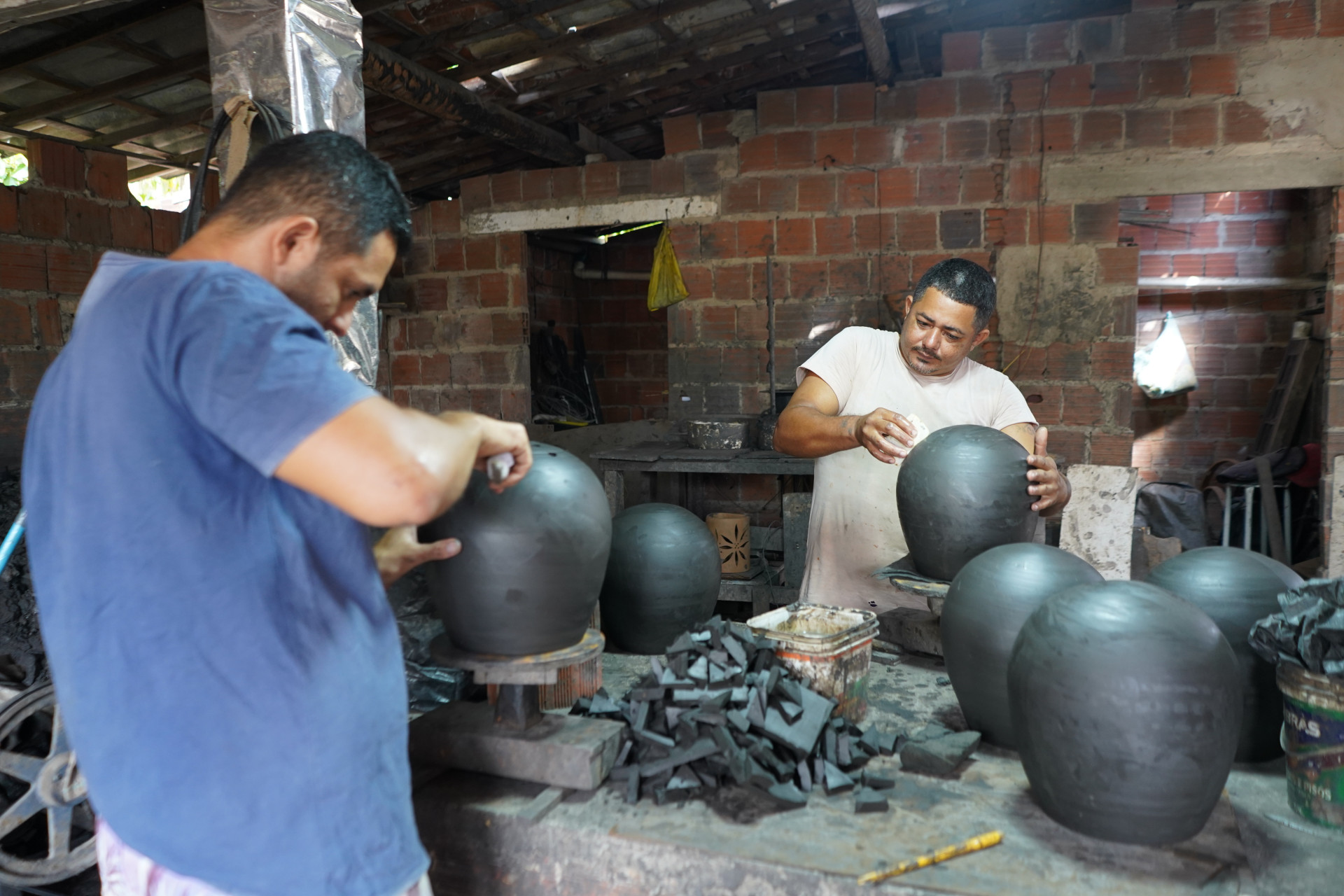 ￼LUCIVALDO da Silva (esq.) e seu filho, Ricardo da Silva, em mais um dia de produção de arte em barro em Moita Redonda (Foto: Marcella Elias/Especial para O POVO)