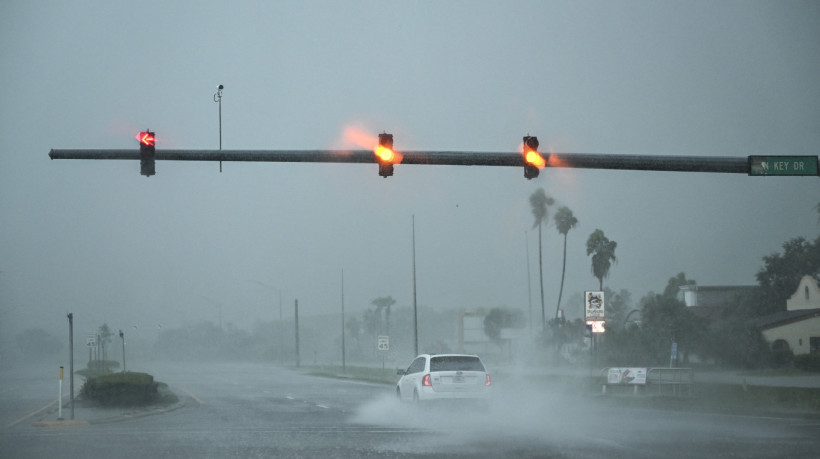 Um carro passa sob forte chuva em Fort Myers, Flórida, em 9 de outubro de 2024, com a aproximação do furacão Milton 