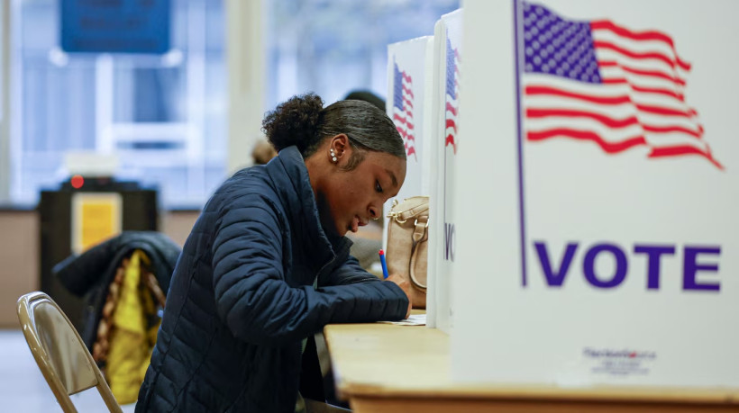 Uma mulher deposita seu voto durante a votação antecipada para a eleição geral dos EUA em uma seção eleitoral na Ottawa Hills High School em Grand Rapids, Michigan