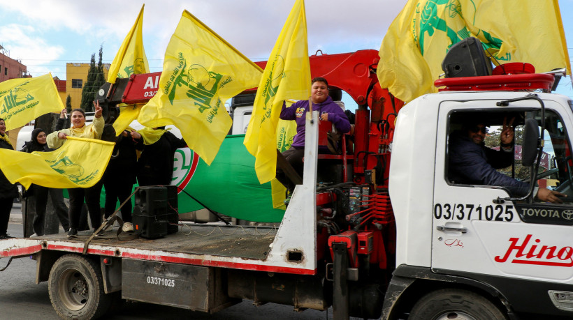 Pessoas agitam a bandeira do movimento libanês Hezbollah enquanto os moradores retornam à cidade de Baalbek, após um cessar-fogo entre o Hezbollah e Israel entrar em vigor.