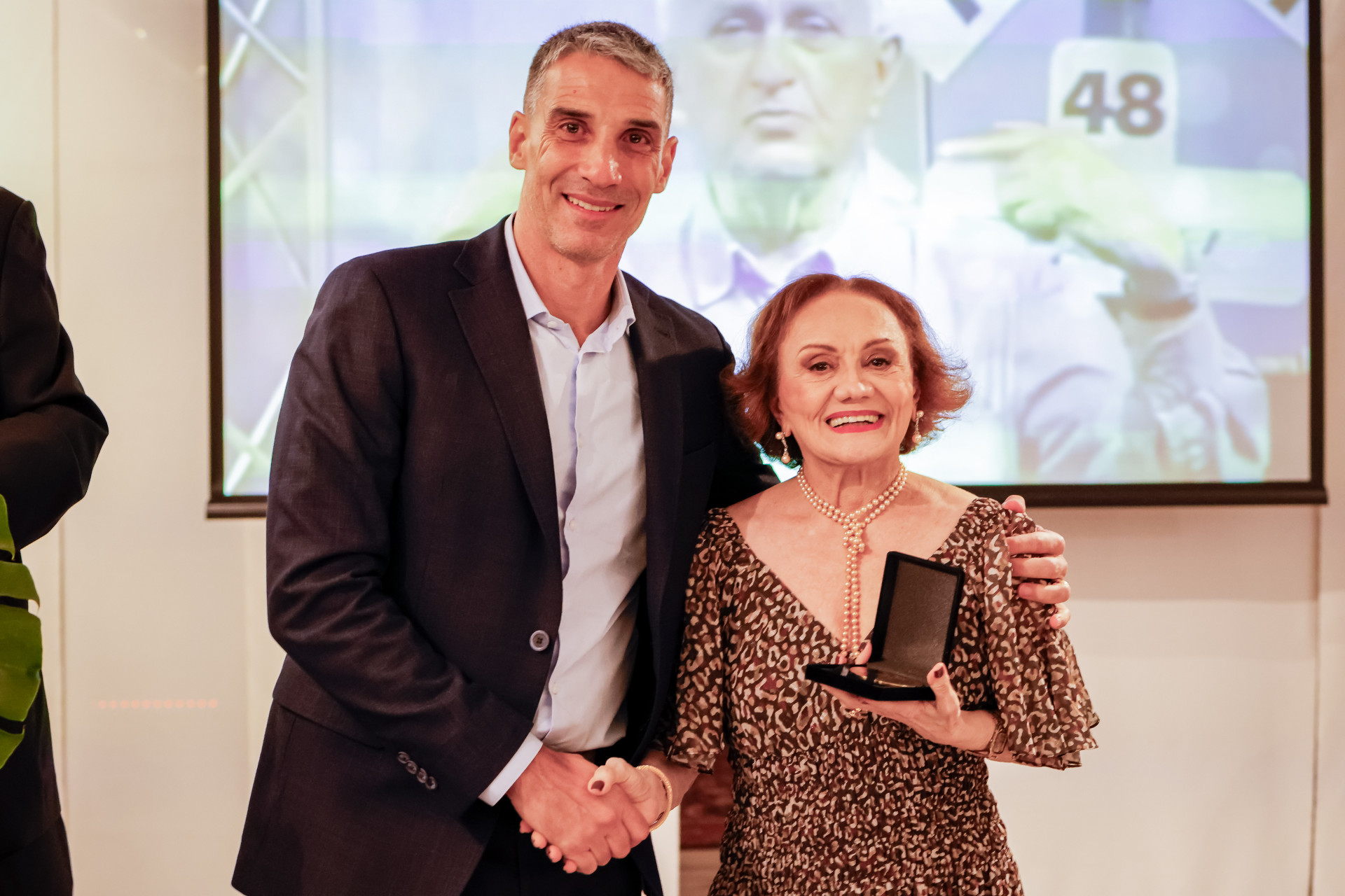 Juan Pablo Vojvoda e Ivoneide Rodrigues, a musa Bette Davis, com imagem de Alan Neto ao fundo (Foto: FOTOS AURÉLIO ALVES
)