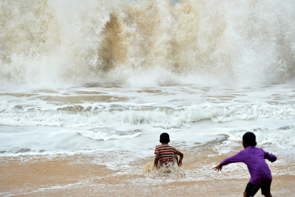 Banhistas do Sri Lanka brincam ao surf na cidade costeira de Peraliya, no sul do país, em 26 de dezembro de 2014, no décimo aniversário do mortífero tsunami asiático(Foto: ISHARA S. KODIKARA/AFP)