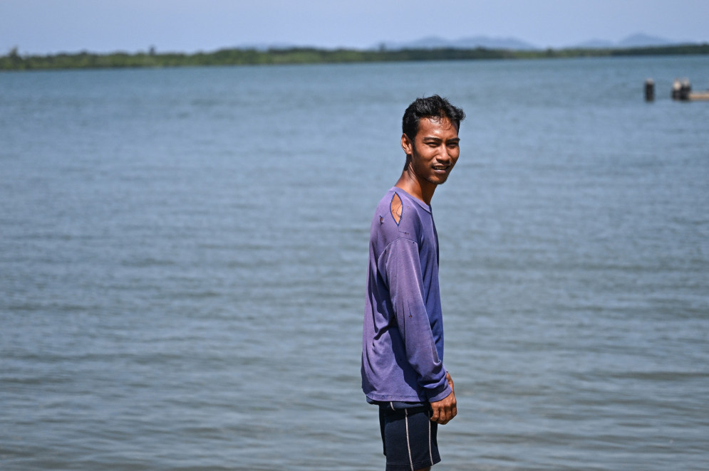 Pirun Kla-Talay, que perdeu os pais Sanoh e Jam Kla-Talay no tsunami do Oceano Índico de 2004. Aqui é visto, em 19 de novembro de 2024, num cais no distrito de Bang Wa, na província de Phang Nga, na Tailândia(Foto: Manan VATSYAYANA / AFP)