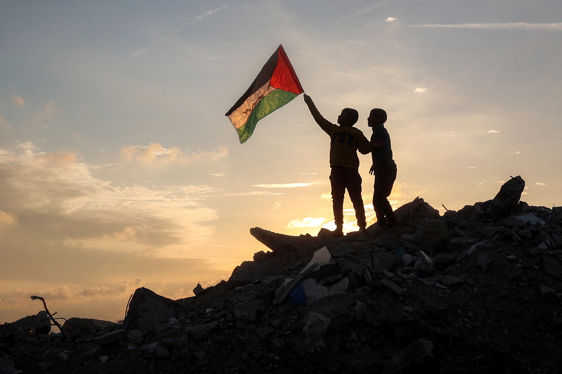 ￼DUAS crianças palestinas correm sobre escombros em um acampamento na Faixa de Gaza (Foto: Eyad BABA / AFP)