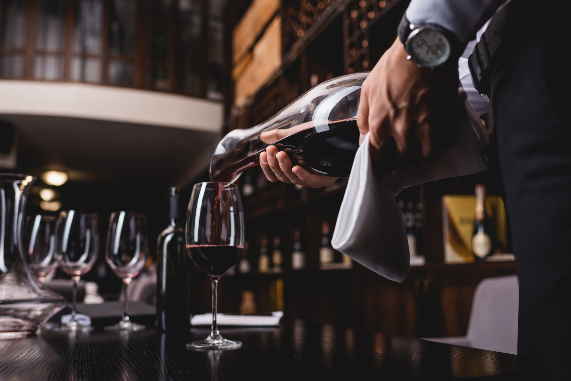 Selective focus of sommelier holding towel and pouring wine in glass on table in restaurant (Foto: adobe stock)