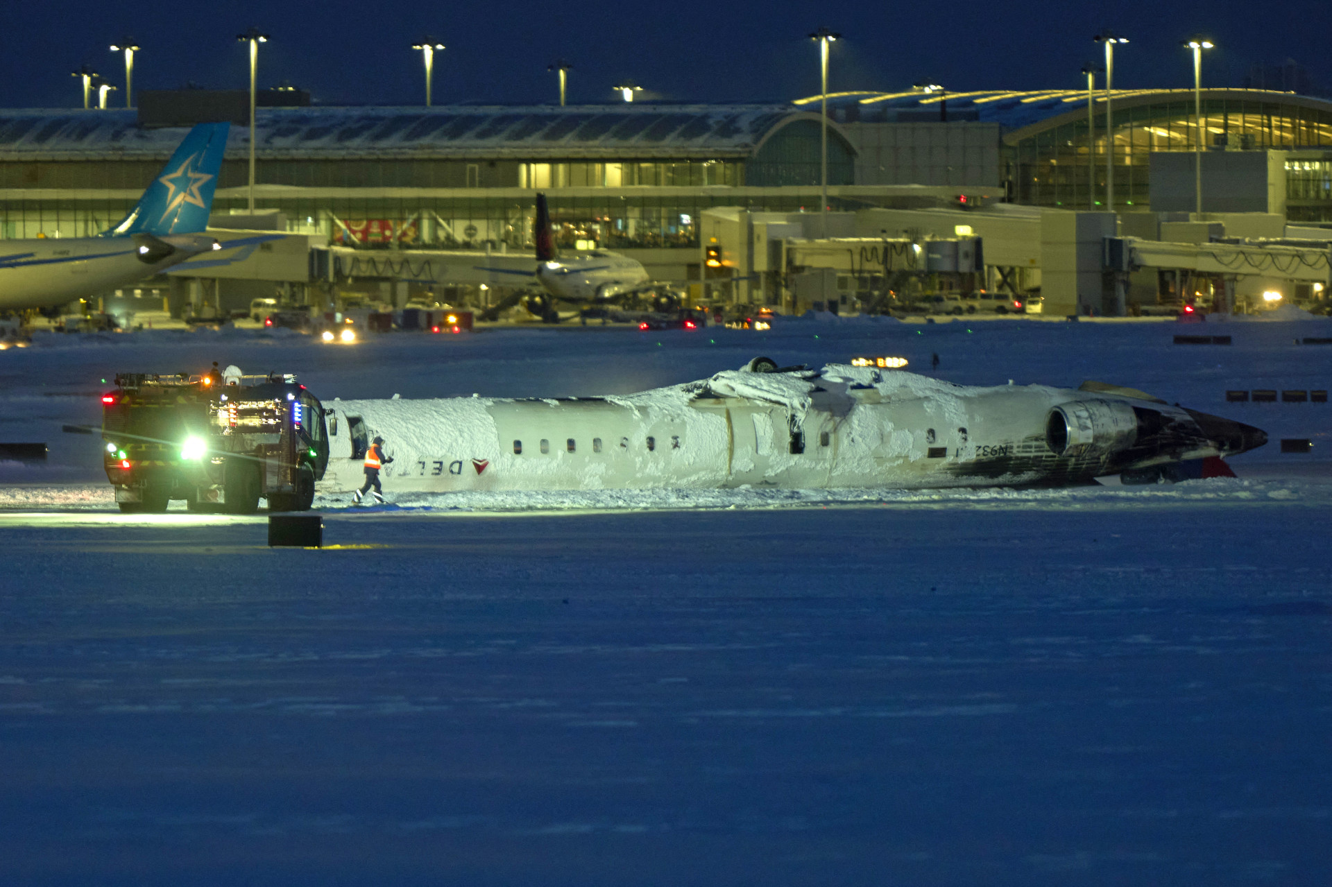 Um avião da Delta Airlines fica em seu teto após cair ao pousar no Aeroporto Toronto Pearson em Toronto, Ontário, em 17 de fevereiro de 2025. Um jato da Delta Air Lines com 80 pessoas a bordo caiu na segunda-feira no aeroporto de Toronto, disseram autoridades, virando de cabeça para baixo e deixando pelo menos 15 pessoas feridas, mas sem causar fatalidades. O voo 4819 da Endeavor Air com 76 passageiros e quatro tripulantes estava pousando por volta das 15h30 na maior metrópole do Canadá, tendo voado de Minneapolis, no estado americano de Minnesota, disse a companhia aérea. (Foto: GEOFF ROBINS/ AFP)