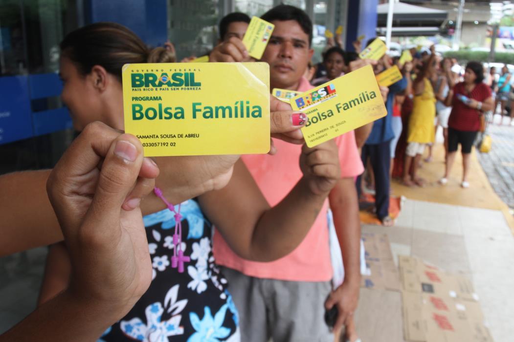  Pessoas seguram cartões do Programa Bolsa Família na fila da agência da Caix...