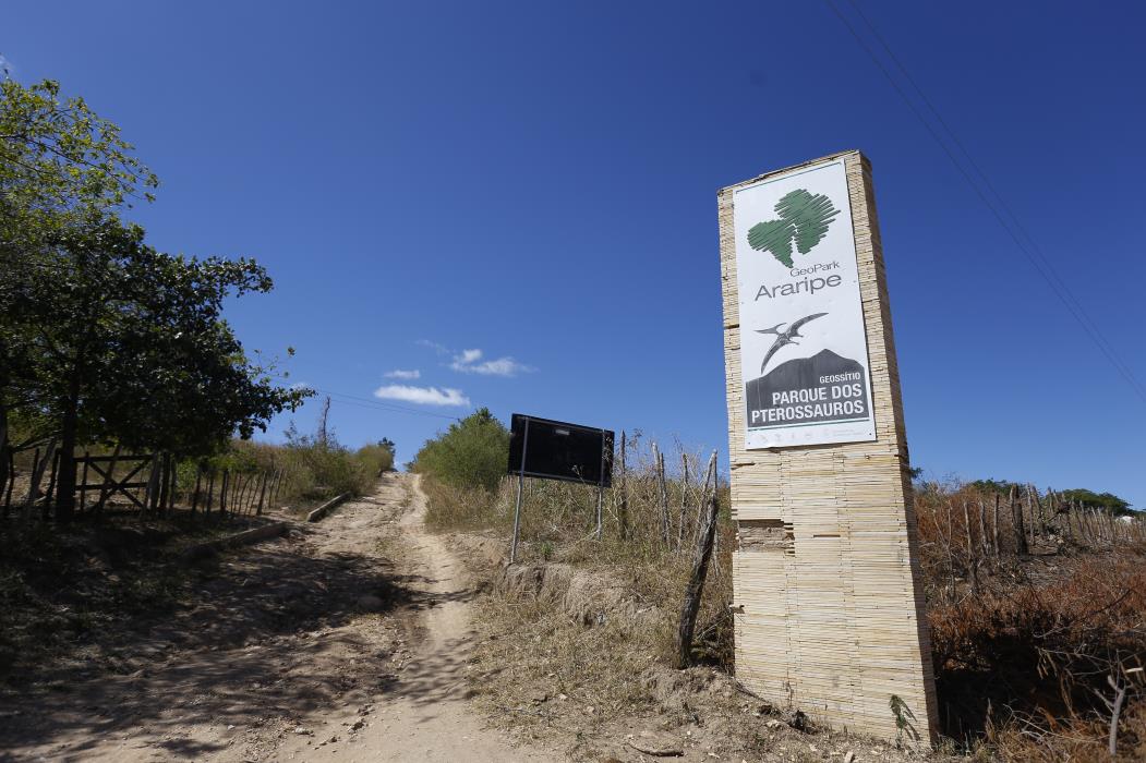 Placa do Geopark Araripe, no pé da Chapada do Araripe (Foto: Tatiana Fortes/O POVO) (Foto: TATIANA FORTES)