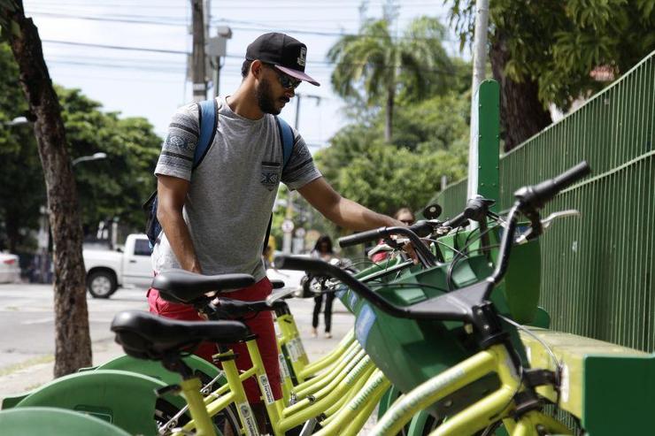 Homem retirando bicicleta da estação de bicicleta compartilhada